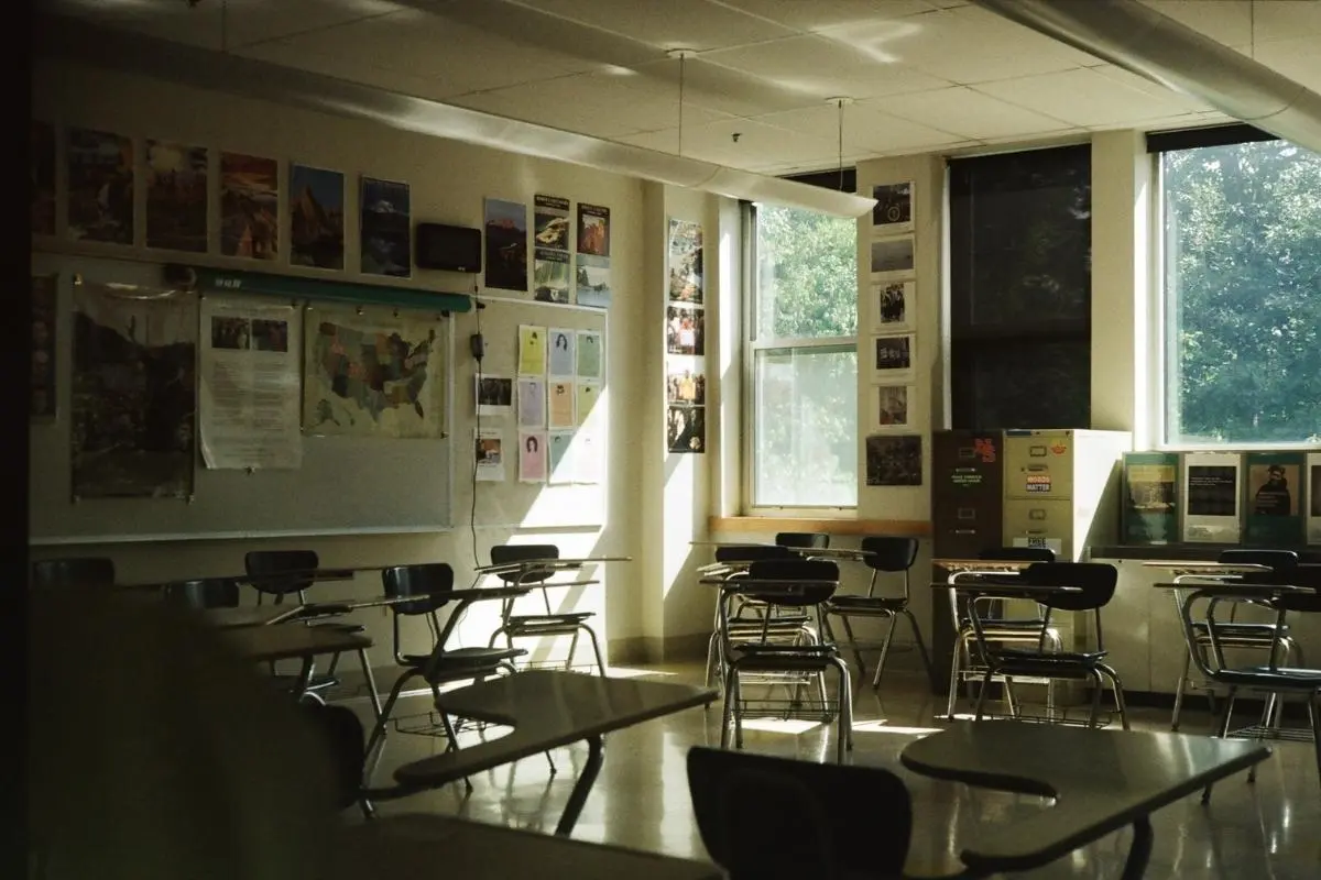 Salle de classe vide exposée au soleil en été, avec stores baissés et lumière crue, montrant un bâtiment public vulnérable à la chaleur.