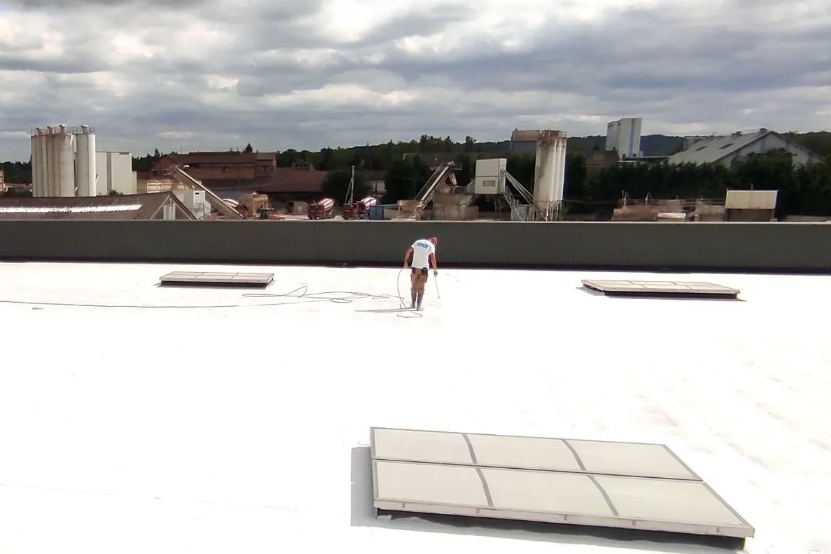 Technicien Cooltech appliquant la peinture réflective PRIMATHERM sur une toiture tertiaire