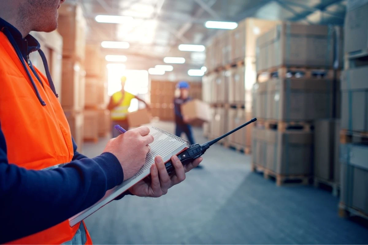 Employé en entrepôt vérifiant les stocks malgré la chaleur en préparation de commandes